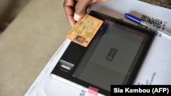 Vérification de l'identité d'un électeur grâce à une tablette dans un bureau de vote, à Port Bouet, lors des élections locales à Abidjan en Côte d'Ivoire le 16 décembre 2018.