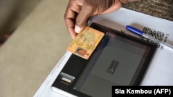 FILE: In the last round of regional and city elections, a vote worker verifies a voter's identity thanks to a tablette at a polling station, in Port Bouet, during the local elections, on December 16, 2018 in Abidjan. 