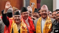 Nepal’s newly-appointed prime minister Khadga Prasad Oli, left, waves to the media as he stands with other leaders of Communist Party of Nepal (Unified Marxist–Leninist), also known as CPN-UML, inside the Constituent Assembly in Kathmandu, Oct. 11, 2015.