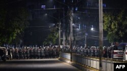 Riot police stand in formation on a road in a residential area in Yangon on February 25, 2021, as tensions rise following weeks of mass demonstrations against the military coup. (Photo by Ye Aung THU / AFP)