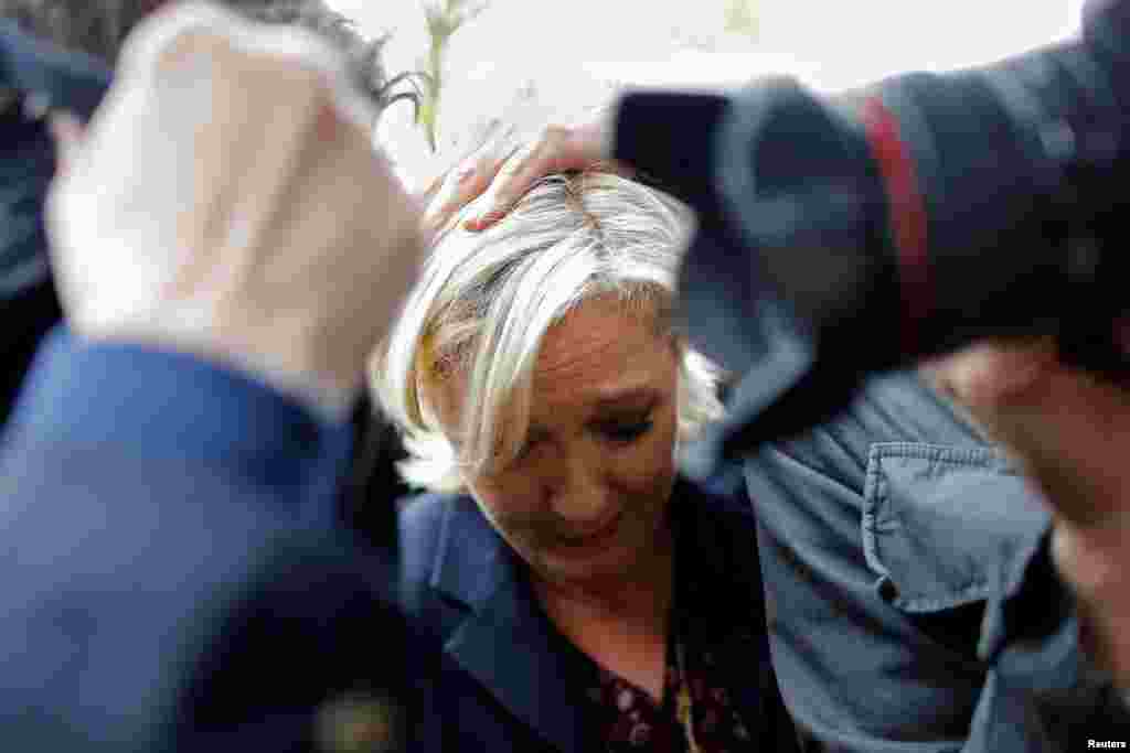 Marine Le Pen, French National Front (FN) party candidate for 2017 presidential election, is protected by bodyguards as demonstrators throw eggs during her arrival in Dol-de-Bretagne.