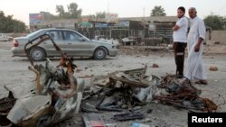 Dua pria mengamati lokasi pasca serangan bom di Baghdad (18/10). Sedikitnya lima orang dilaporkan tewas dan belasan terluka dalam insiden ini.