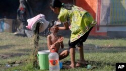 A woman bathes a child at a temporary shelter in Palu, Central Sulawesi, Indonesia, Oct. 4, 2018, after parts of the province were hit by a powerful earthquake and tsunami. (AP Photo/Tatan Syuflana)