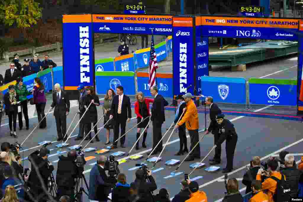 Marathon and government officials take part in the ceremonial painting of the New York City Marathon blue line at Central Park, New York, Oct., 2013. 