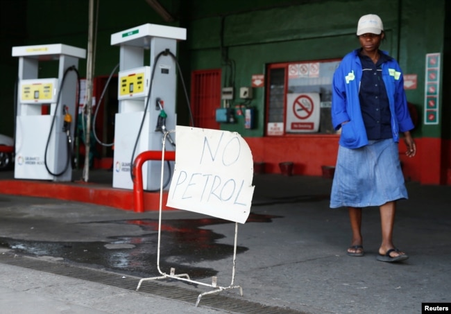 A woman walks past a "No Petrol" sign at a fuel station in Harare, Zimbabwe, Oct. 9, 2018.
