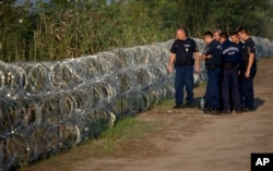 Hungarian police inspect a barbed wire fence on the border with Serbia, in Roszke, Hungary, Aug. 29, 2015.