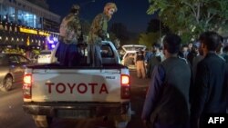 Des combattants talibans se tiennent sur une camionnette à l'extérieur d'un hôpital, alors que des bénévoles amènent des blessés pour les soigner après deux puissantes explosions à l'extérieur de l'aéroport de Kaboul, le 26 août 2021.