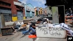 Un manifestante antigubernamental empuja un refrigerador para hacer una barricada en Caracas.