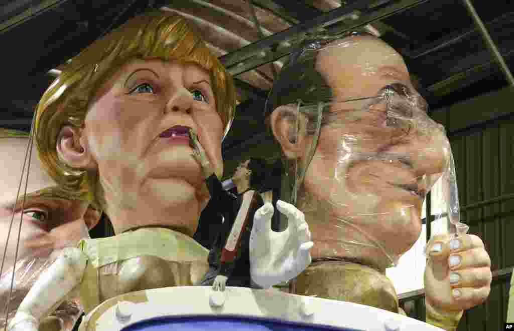 A man puts the final touches on a giant figure showing German Chancellor Angela Merkel, next to France&#39;s President Francois Hollande during preparations for the 131st Nice carnival parade in Nice, southeastern France.