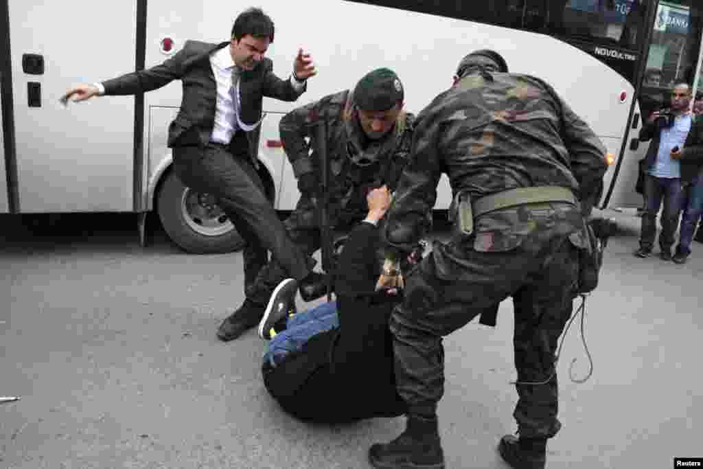 A protester is kicked by Yusuf Yerkel (L), advisor to Turkey's Prime Minister Tayyip Erdogan. Special Forces police officers detain him during a protest against Erdogan's visit in the province of Manisa, May 14, 2014.
