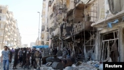 Warga dan anggota keamanan sipil memeriksa sebuah bangunan yang hancur pasca serangan udara di wilayah Tariq al-Bab, Aleppo, Suriah (23/4).