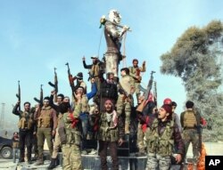 Turkey-backed Free Syrian Army soldiers celebrate around a statue of Kawa, a mythology figure in Kurdish culture as they prepare to destroy it in city center of Afrin, northwestern Syria, March 18, 2018.