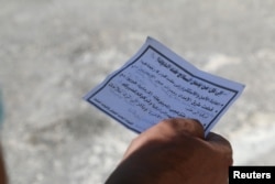 A man holds one of the leaflets dropped by the Syrian army over opposition-held Aleppo districts asking residents to cooperate with the military and calling on fighters to surrender, July 28, 2016.