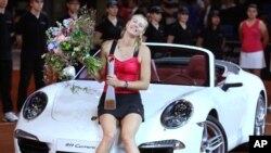 FILE - Russia's Maria Sharapova sits on a Porsche Carrera after beating Belarus' Victoria Azarenka in the final of the Porsche Tennis Grand Prix in Stuttgart, Germany, Apr. 29, 2012.