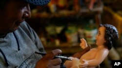 El artesano Ramiro Suxo da los toques finales a una estatuilla del Niño Jesús en un taller en El Alto, Bolivia, el lunes 13 de diciembre de 2021. (AP Foto/Juan Karita)
