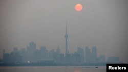 The sun rises through a cover of wildfire smoke above the CN Tower and downtown skyline in Toronto, Ontario, Canada July 20, 2021. (REUTERS/Carlos Osorio)