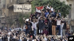 Egyptian anti-government protesters climb atop an Egyptian army armored personnel carrier, next to a signpost bearing the words "Down Mubarak", in Cairo,January 29, 2011