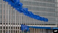 Workers adjust the EU flags in front of EU headquarters in Brussels, Belgium, June 22, 2016. Voters in the United Kingdom are taking part in a referendum that will decide whether Britain remains part of the European Union or leaves the 28-nation bloc. 