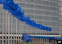 FILE - Workers adjust the EU flags in front of EU headquarters in Brussels, Belgium, June 22, 2016.