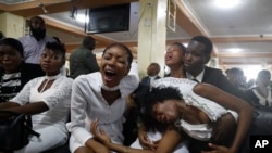 Familiares del asesinado líder comunitario haitiano Josemano "Badou" Victorieux lloran durante el funeral en Puerto Príncipe, Haití, el miércoles, 16 de octubre del 2019. (AP Foto/Rebecca Blackwell).