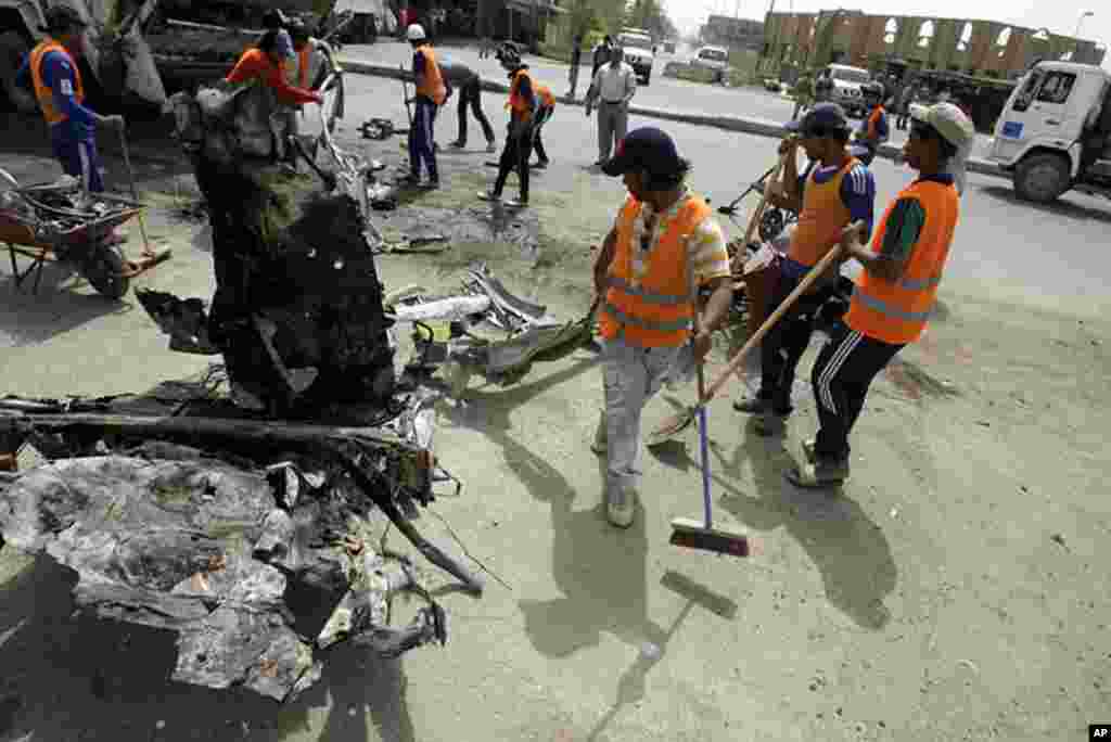 Iraqis remove the debris following a blast in central Baghdad as a wave of bombings and shootings across Iraq killed at least 35 people and wounded dozens more, April 19, 2012. (AFP)