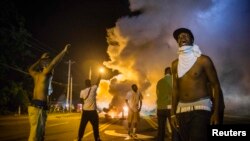 U.S. -- Demonstrators stand in the middle of a St.Louis area street as they react to tear gas fired by police during ongoing protests in reaction to the shooting of teenager Michael Brown, near Ferguson, Missouri, August 18, 2014.