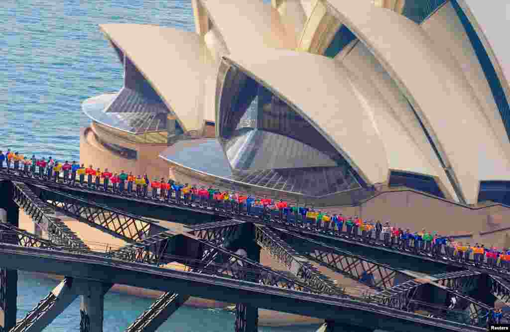 The Sydney Opera House is seen behind some of the 360 university students from Canada and China as they stand atop of the Sydney Harbour Bridge to set a new record for the most number of people standing on the bridge arc at one time, in Sydney, Australia.