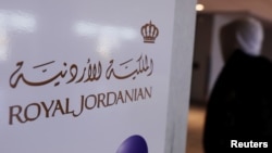 ນັກທ່ອງທ່ຽວຍ່າງຜ່ານປ້າຍຂອງສາຍການບິນ Royal Jordanian ທີ່ສະໜາມບິນສາກົນ JFK ໃນນະຄອນນິວຢອກ, ສະຫະລັດ.