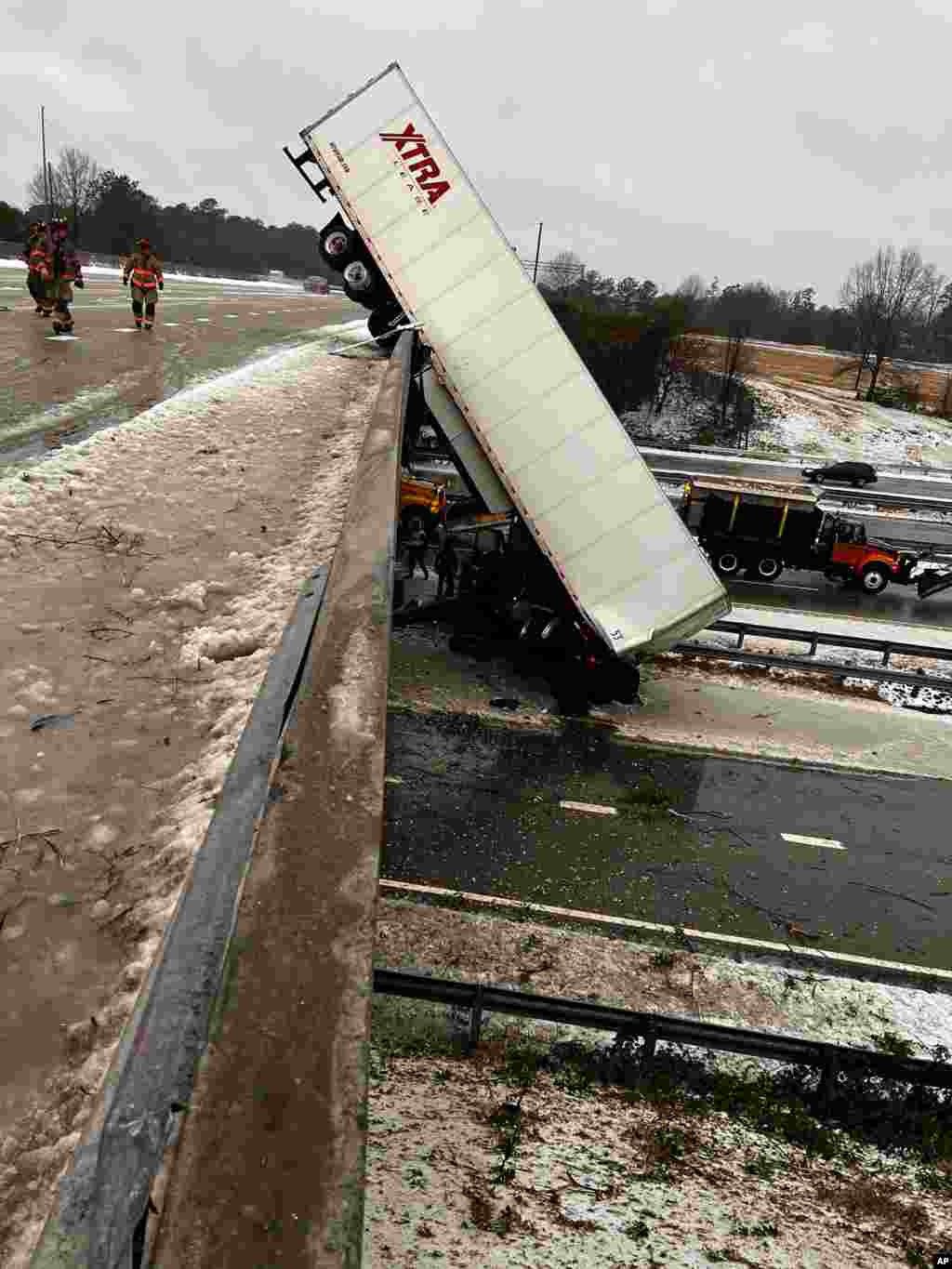 In this photo provided by the Durham Police Department, a truck hangs from the highway N.C. 147 overpass after its cab apparently slid off the highway during winter weather, Jan. 16, 2022, in Durham, North Carolina.