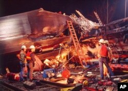 FILE - Workmen survey the damage from the collision between an Amtrak passenger train and three Conrail diesel engines, in Chase Md., Jan 4, 1987. Sixteen people were killed and more than 170 injured in the collision.