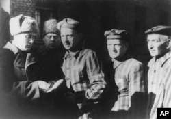 FILE- In this file photo dated January 1945, three Auschwitz prisoners, right, talk with Soviet soldiers after the Nazi concentration camp Auschwitz, in Poland, was liberated by the Russians.