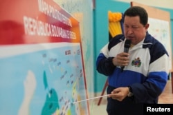 FILE - Hugo Chavez points at a Venezuela map during a visit to a facility in Morichal, Aug. 21, 2012.