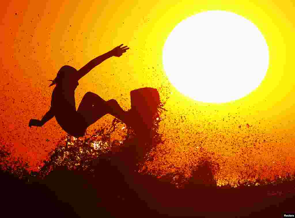 Surfer Cole Clisby rides his surfboard off the top of a wave as the sun sets off the shores of Leucadia, California, Jan. 15, 2014. 