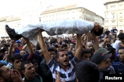 Protesting migrants from Afghanistan and Syria hold up a child wrapped in blankets, as a reminder of the horrors they have fled, while demonstrating outside the shuttered Keleti Railway Station in Budapest, Hungary, Sept. 2, 2015.