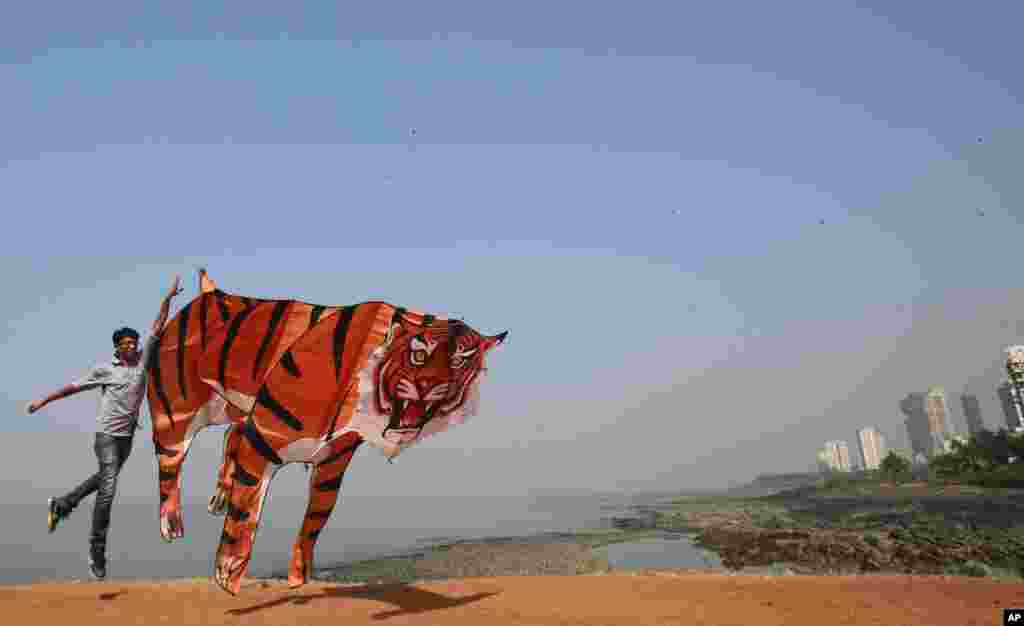 A participant runs with a large tiger-shaped kite at the International Kite Festival in Mumbai, India.