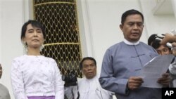 ျမန္မာ့ဒီမိုကေရစီေခါင္းေဆာင္ ေဒၚေအာင္ဆန္းစုၾကည္ႏွင့္ ျမန္မာအလုပ္သမားနဲ႔ လူမႈ၀န္ထမ္းကယ္ဆယ္ေရးဌာန ၀န္ႀကီး ဦးေအာင္ၾကည္တို႔ စိမ္းလဲ့ကန္သာ အစိုးရဧည့္ေဂဟာတြင္ ေဆြးေႏြးမႈအၿပီး သတင္းေထာက္မ်ားႏွင့္ ေတြ႔ဆံုေနစဥ္ (ၾသဂုတ္လ ၁၂၊ ၂၀၁၁)