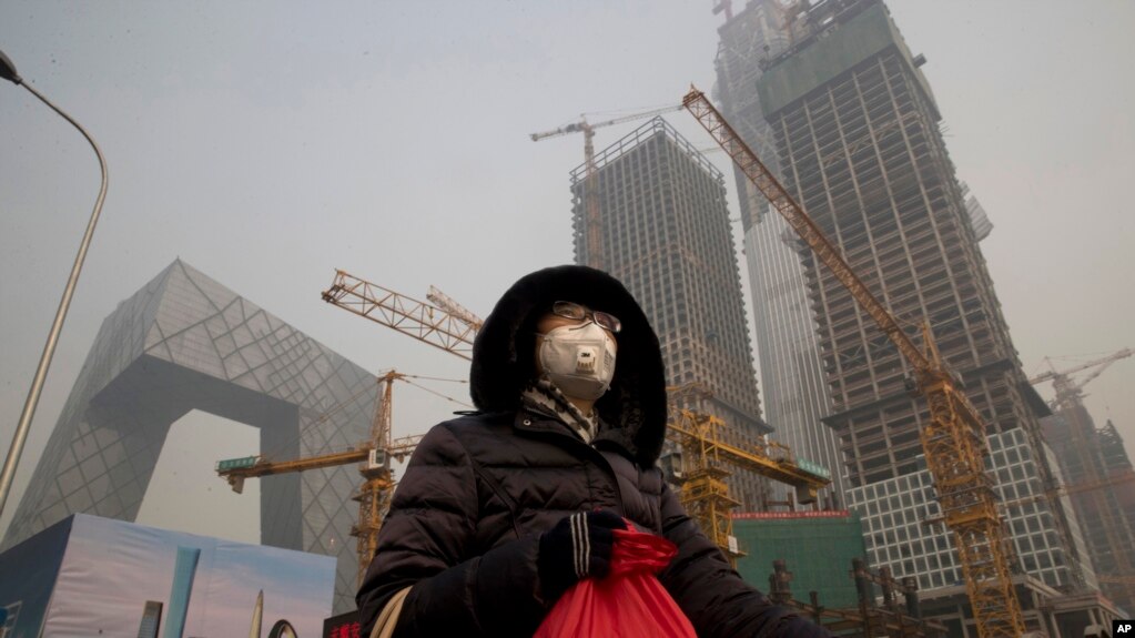 在雾霾中，行人戴口罩在北京中央商务区的央视大楼旁边的施工工地走过（1017年1月6日）