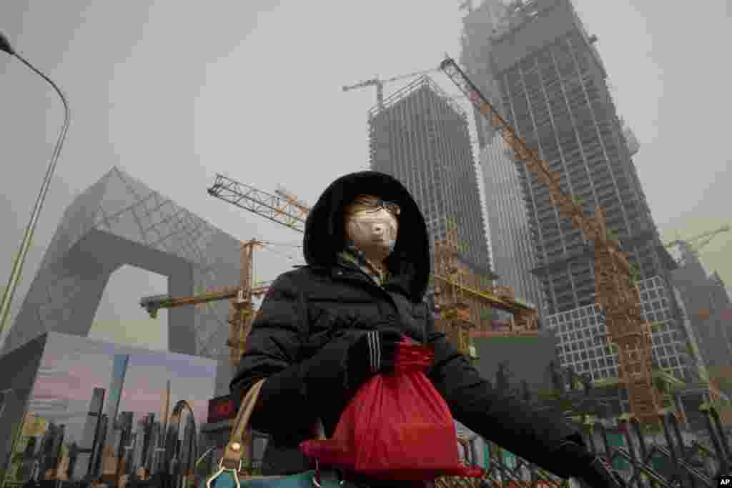 2017年1月6日，在雾霾中，有人戴口罩在北京中央商务区的央视大楼旁边的施工工地走过