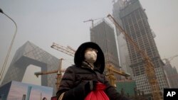 在雾霾中，行人戴口罩在北京中央商务区的央视大楼旁边的施工工地走过（1017年1月6日）