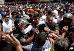 Opposition leader Leopoldo Lopez, dressed in white and holding up a flower stem, is taken into custody by Bolivarian National Guards, in Caracas, Venezuela, Feb 18, 2014.