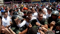 Opposition leader Leopoldo Lopez, dressed in white and holding up a flower stem, is taken into custody by Bolivarian National Guards, in Caracas, Venezuela, Feb 18, 2014.