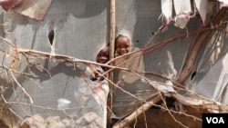 Two girls peer into the compound of Abdulaziz Yassir Kuku, their Sudanese neighbor who was scheduled to fly from Kakuma refugee camp to Nairobi on January 30, for processing for his resettlement in Des Moines, Iowa. The U.S. travel ban prevented him from doing so. He now waits for more information in Kakuma, Kenya, Feb. 6, 2017. (J. Craig / VOA)