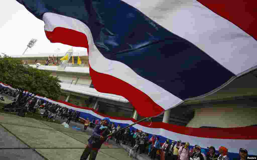An anti-government protester waves a Thai national flag at the gymnasium where candidates register for&nbsp; upcoming elections in Bangkok, Dec. 25, 2013. 