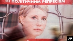 People pass by a poster of Ukraine's imprisoned former prime minister Yulia Tymoshenko at a tent camp of her supporters in central Kyiv, Ukraine, in this April 30, 2013, file photo. The text on top reads: "No to political repressions."