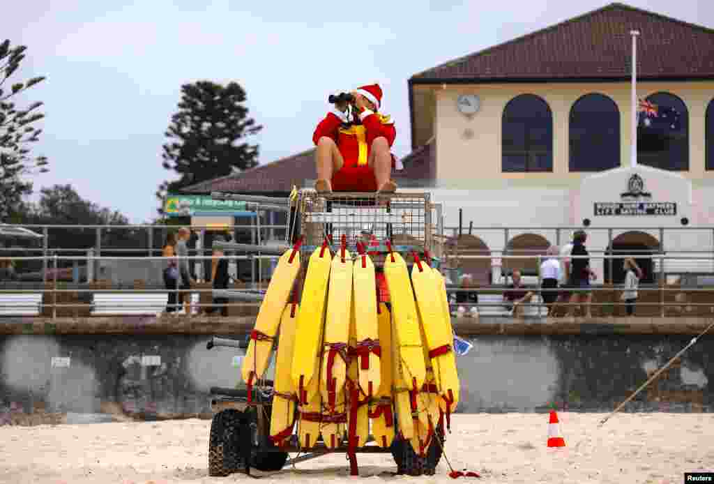 A surf lifesaver wearing a Christmas hat uses binoculors to watch swimmers on Christmas Day at Sydney&#39;s Bondi Beach in Australia.