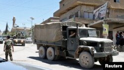 FILE - A convoy of Lebanese army soldiers drives at the entrance of the border town of Arsal, in eastern Bekaa Valley, Lebanon, June 30, 2017.