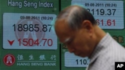 A man passes a screen displaying the Hong Kong Stock index, Aug. 2011 (file photo).
