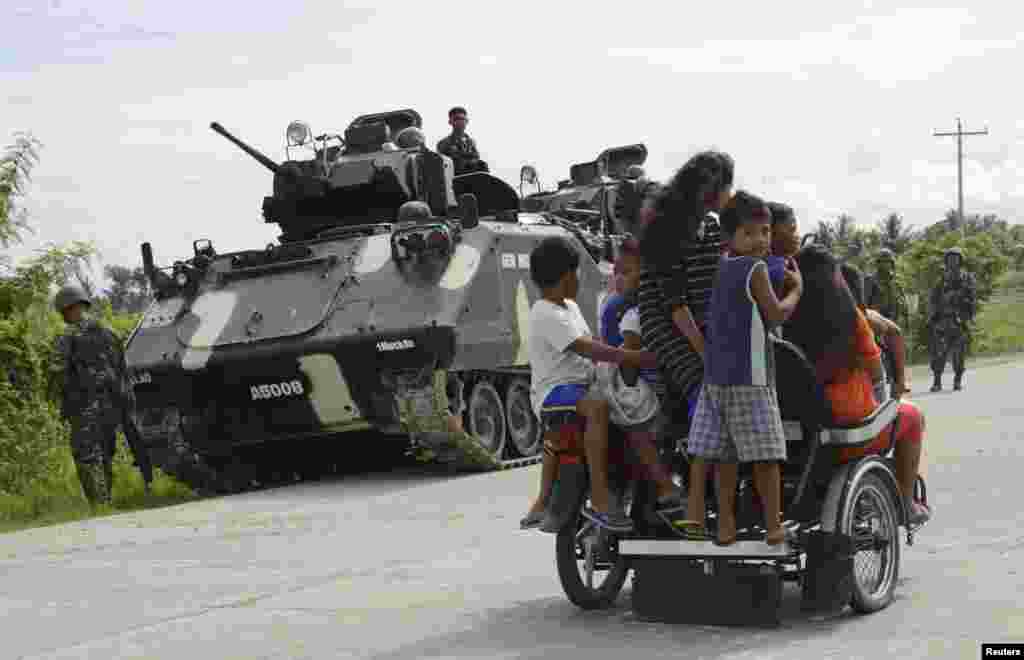 Residents ride a tricycle past soldiers on a patrol ahead of the midterm elections, in Shariff Aguak, Maguindanao in southern Philippines, May 12, 2013. 