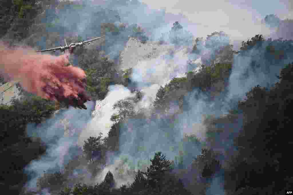 Sebuah pesawat menjatuhkan zat penghambat kobaran api untuk mengatasi kebakaran hutan di Rigaud, sebelah utara kota Nice, Perancis.