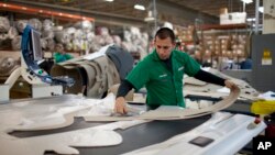 FILE - A worker manufactures car dash mats at a factory belonging to the TECMA group in Ciudad Juarez, Mexico, Dec. 27, 2013.